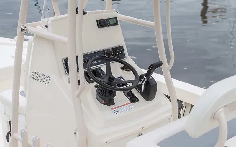 Slide: The Image of 2025 Pathfinder 2200 TRS boat console with steering wheel and controls by the water. - 3