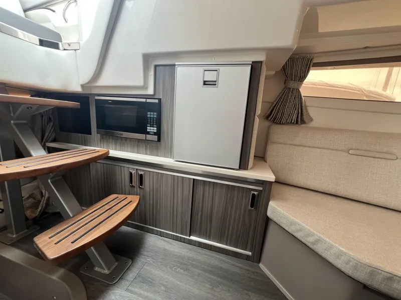 Slide: The Image of 2023 Sea Ray Sundancer 320 interior with kitchenette, microwave, fridge, and seating area. - 28