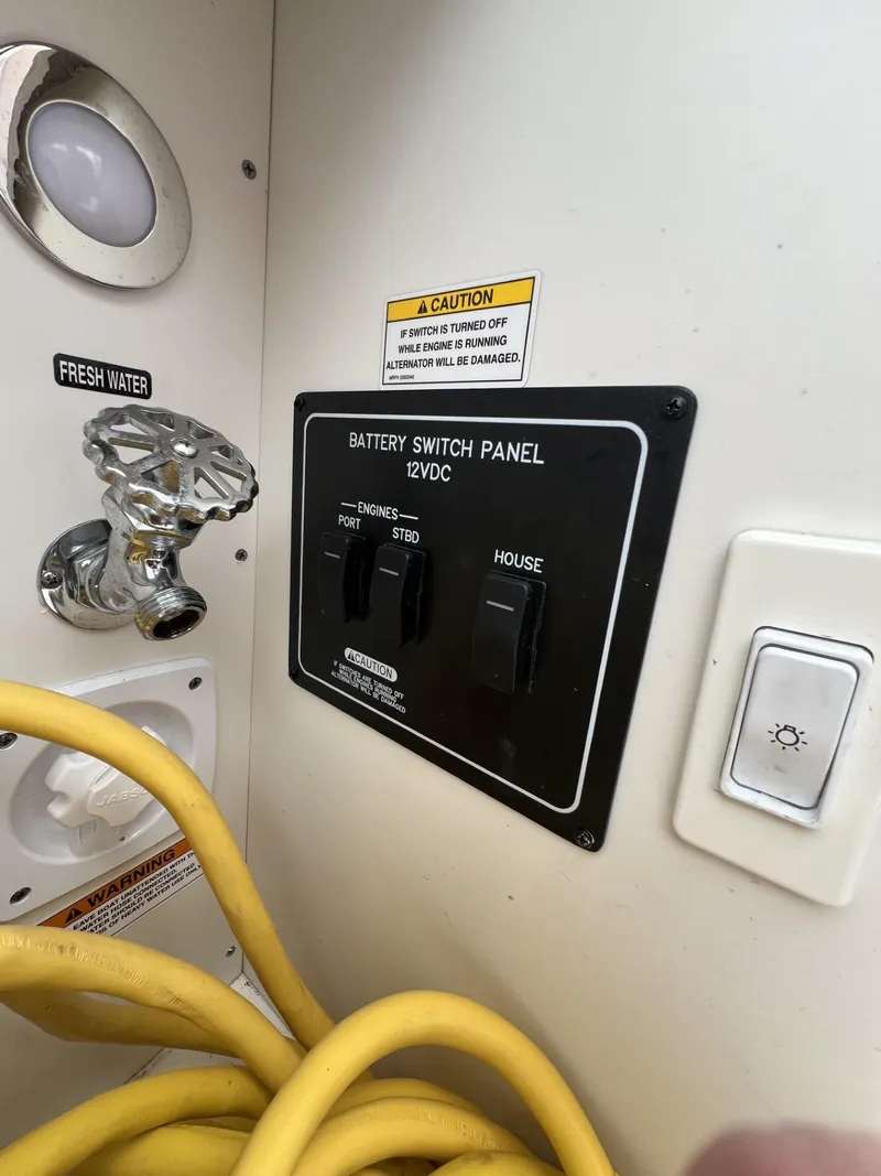 Slide: The Image of 2023 Sea Ray Sundancer 320 battery switch panel with fresh water access and caution label. - 33