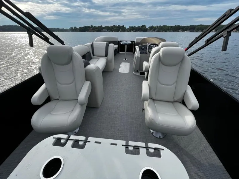 Slide: The Image of 2025 Sylvan Mirage X3 Party Fish pontoon boat interior with plush seating on a serene lake. - 11