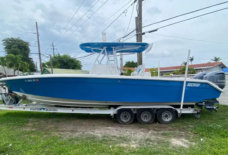 Slide: The Image of Blue 2019 Sea Tech 33 boat on trailer, parked on grass. - 1