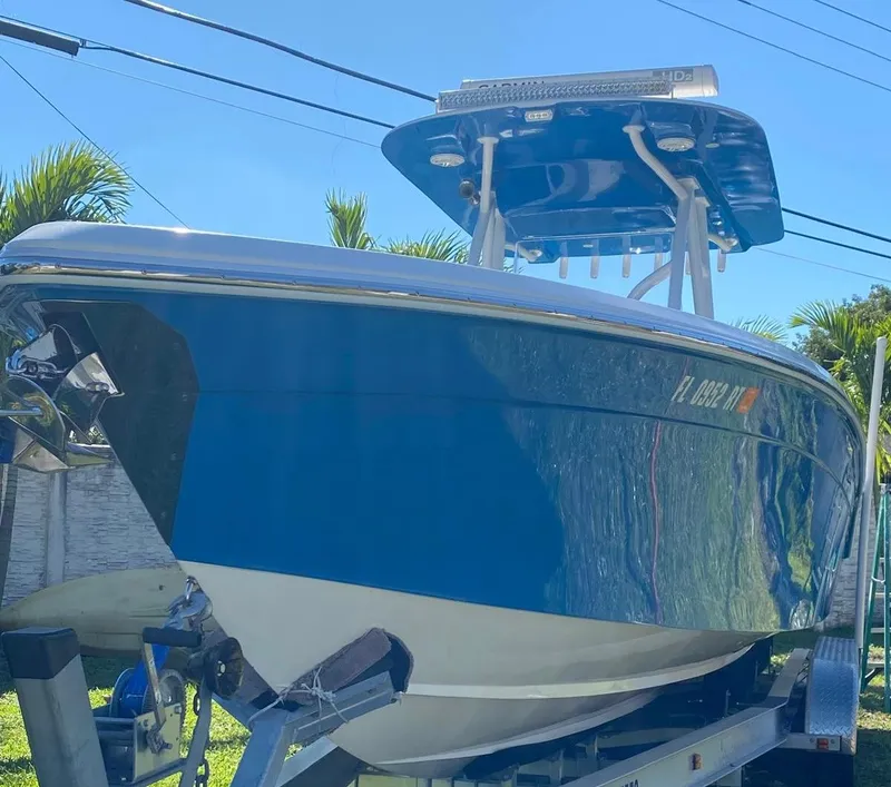 Slide: The Image of 2019 Sea Tech 33 boat on trailer, blue hull, sunny day, palm trees in background. - 19