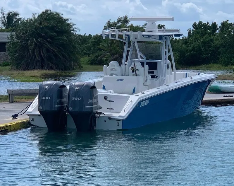 Slide: The Image of 2019 Sea Tech 33 boat with dual Yamaha 300 engines docked in serene waters. - 2