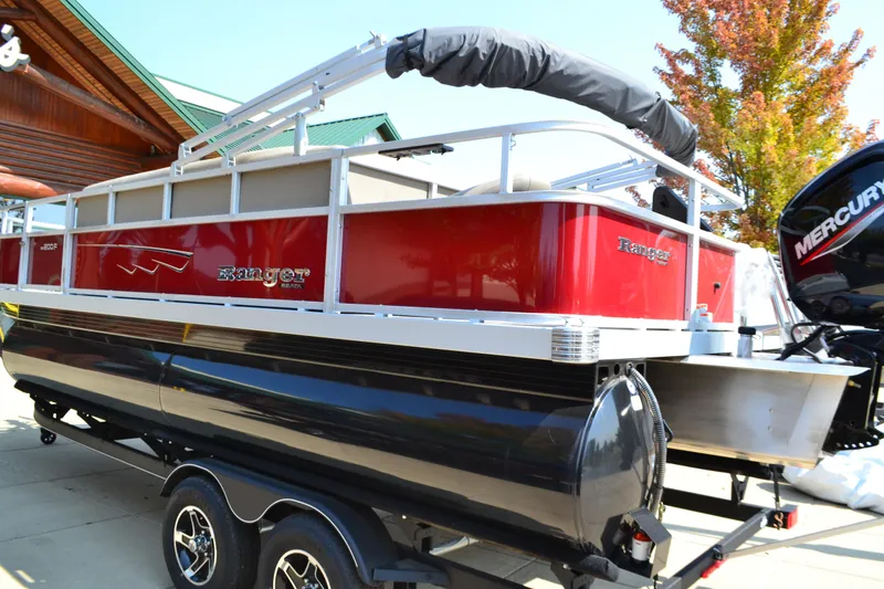 Slide: The Image of 2024 Ranger Reata 200F pontoon boat with red and black design on a trailer. - 0