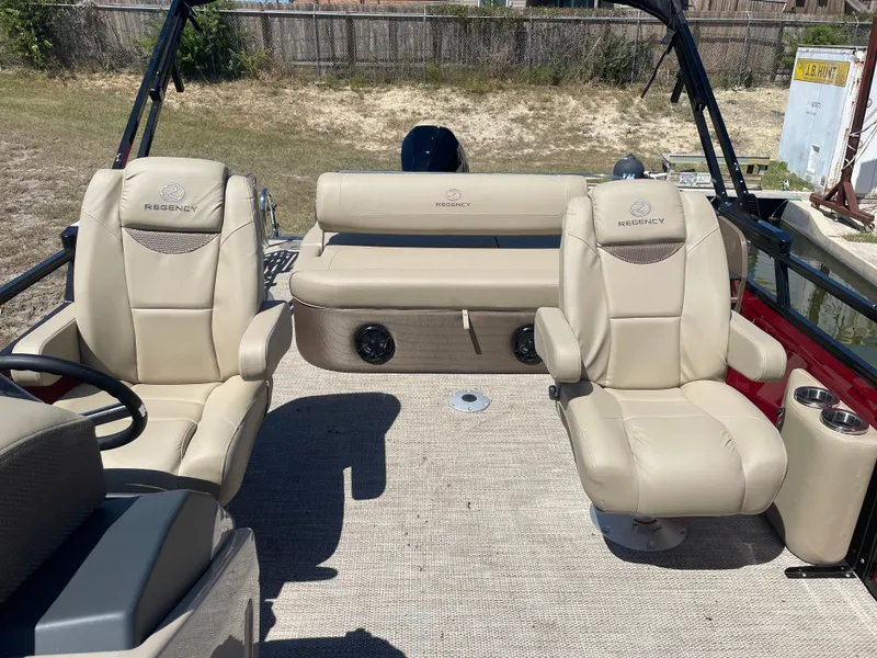 Slide: The Image of 2024 Regency 230 LE3 Sport boat interior with beige seating and steering wheel. - 2