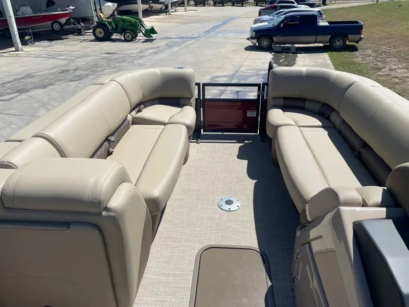 Slide: The Image of 2024 Regency 230 LE3 Sport pontoon boat with spacious beige seating and open deck. - 3