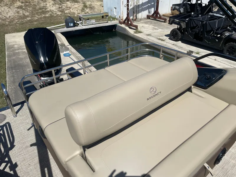 Slide: The Image of 2024 Regency 230 LE3 Sport boat with beige seating near a dock. - 5