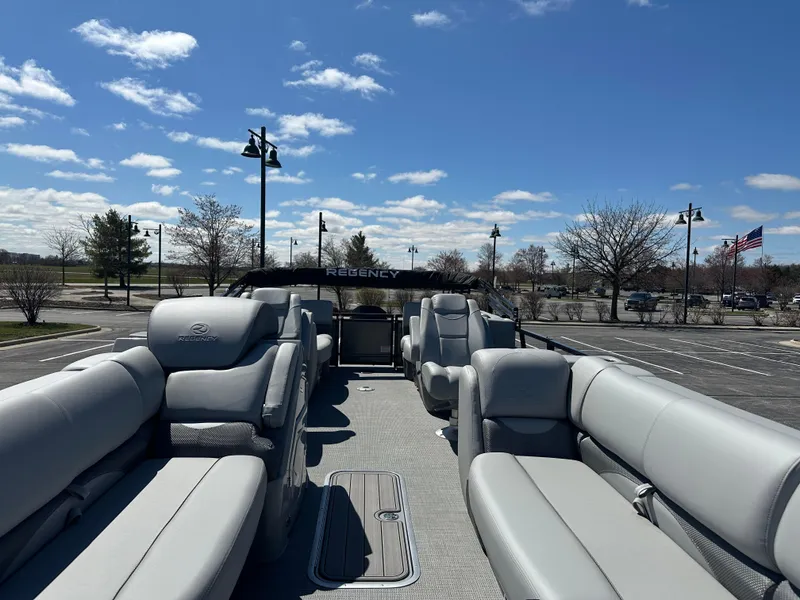 Slide: The Image of 2024 Regency 230 DL3 pontoon boat with spacious seating under a clear blue sky. - 2