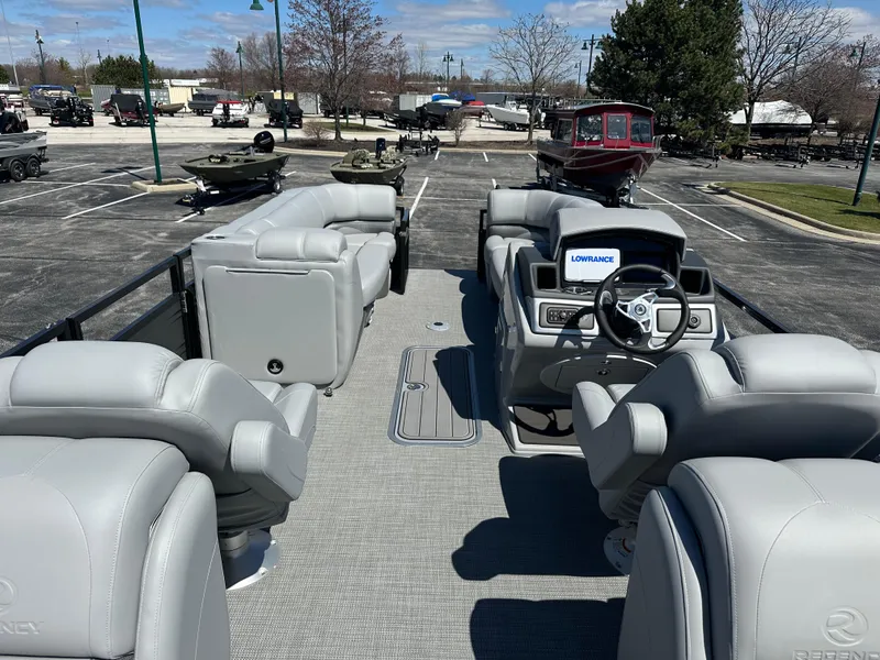 Slide: The Image of 2024 Regency 230 DL3 pontoon boat with luxurious seating and modern dashboard in a parking lot. - 4
