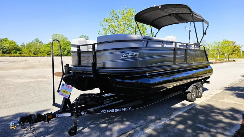 Slide: The Image of 2024 Regency 230 LE3 Sport pontoon boat on trailer, parked outdoors. - 4