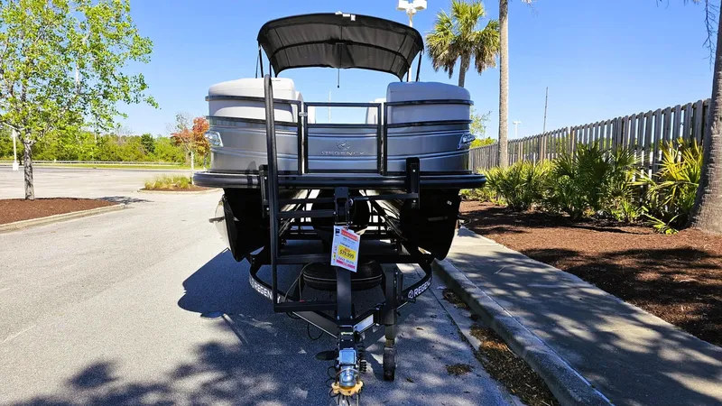 Slide: The Image of 2024 Regency 230 LE3 Sport pontoon boat on trailer, parked outdoors. - 5