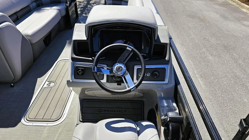 Slide: The Image of 2024 Regency 230 LE3 Sport boat interior with steering wheel and seating. - 9