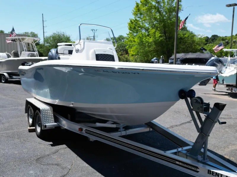 Slide: The Image of 2023 Tidewater 198CC boat on trailer, displayed outdoors with trees and flags in the background. - 7