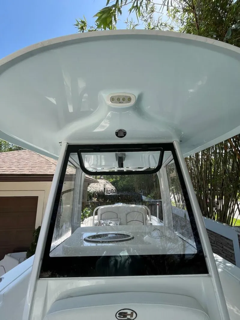 Slide: The Image of 2018 Sea Hunt 255 SE boat with T-top and console, docked near greenery. - 15