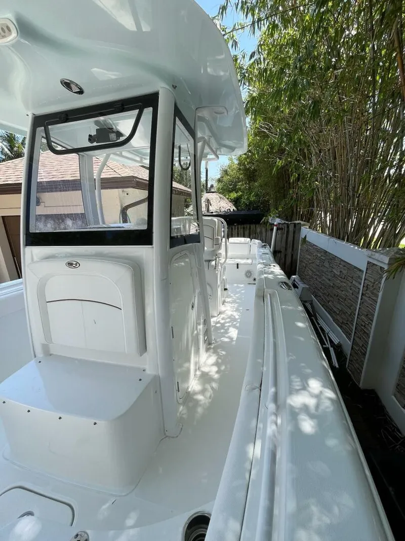 Slide: The Image of 2018 Sea Hunt 255 SE boat with sleek white design, docked near bamboo plants. - 17