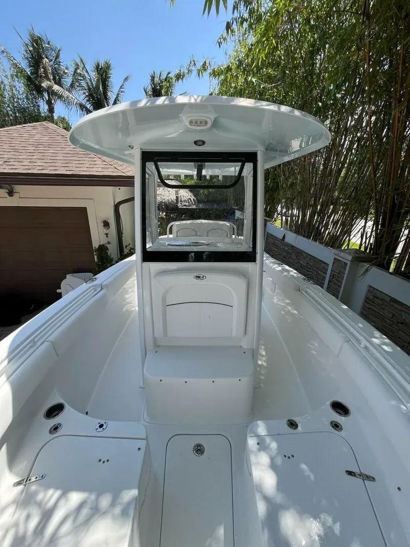 Slide: The Image of 2018 Sea Hunt 255 SE boat with center console, parked outdoors, surrounded by trees. - 19