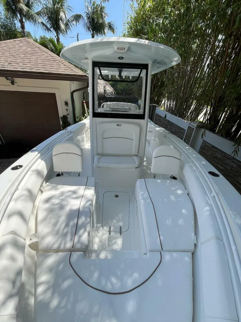 Slide: The Image of 2018 Sea Hunt 255 SE boat with spacious deck and seating, surrounded by tropical foliage. - 20