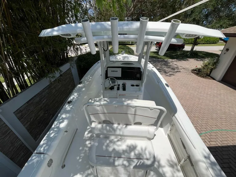 Slide: The Image of 2018 Sea Hunt 255 SE boat with center console and rod holders, parked in a driveway. - 29