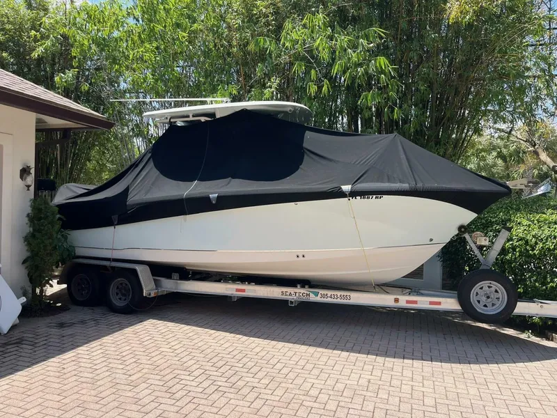 Slide: The Image of 2018 Sea Hunt 255 SE boat covered on a trailer, parked in a driveway. - 40