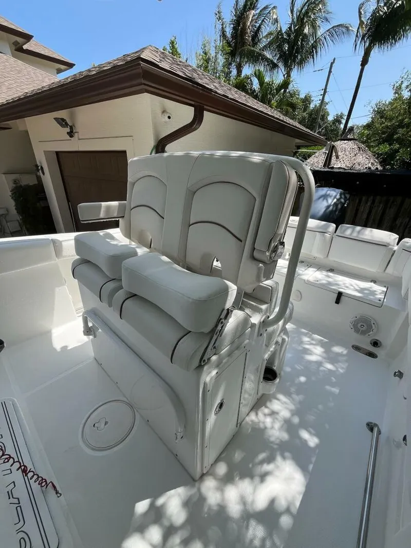 Slide: The Image of 2018 Sea Hunt 255 SE boat interior with cushioned seating, docked near tropical foliage. - 9