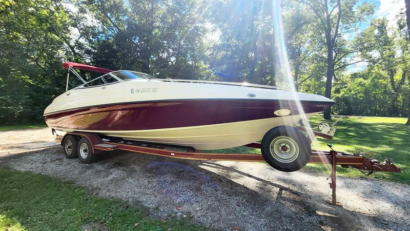 Slide: The Image of 1996 Crownline 266 BR boat on trailer, parked outdoors in a sunny, wooded area. - 10