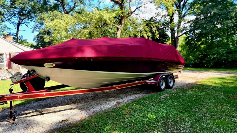 Slide: The Image of 1996 Crownline 266 BR boat with red cover on trailer, parked outdoors. - 14