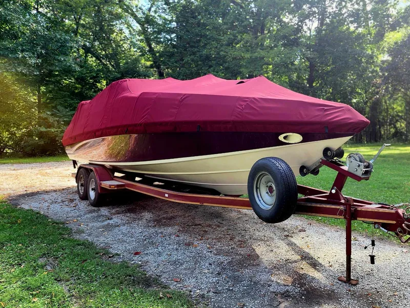 Slide: The Image of 1996 Crownline 266 BR boat on trailer, covered with red tarp, parked outdoors. - 15