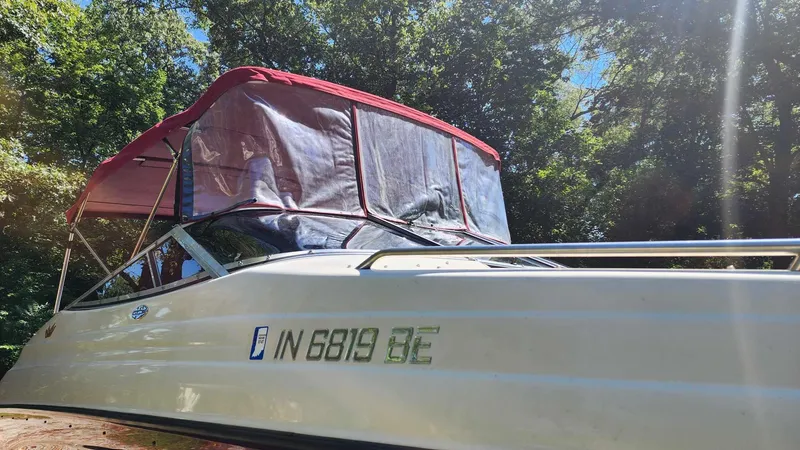 Slide: The Image of 1996 Crownline 266 BR boat with red canopy, parked outdoors under trees. - 4