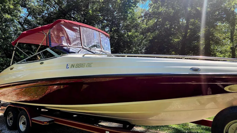 Slide: The Image of 1996 Crownline 266 BR boat with red canopy on trailer, surrounded by trees. - 6