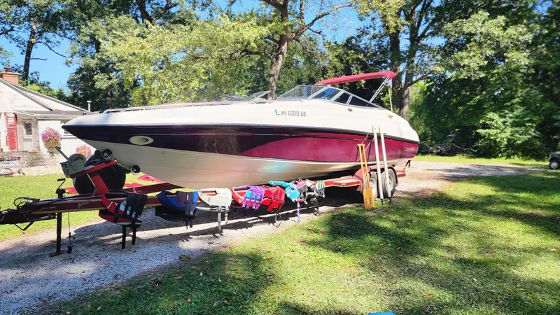 Slide: The Image of 1996 Crownline 266 BR boat on trailer, parked outdoors with trees in the background. - 7