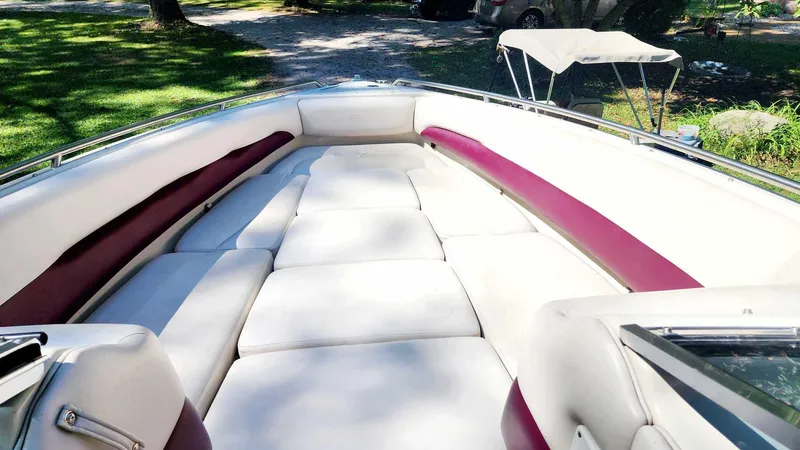 Slide: The Image of 1996 Crownline 266 BR boat interior with white and maroon seating, sunny day. - 9