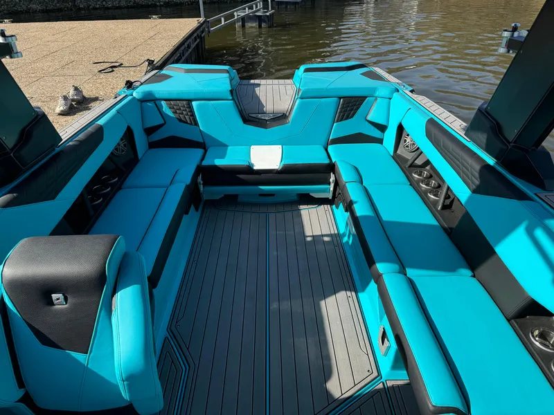 Slide: The Image of 2023 Nautique Super Air Nautique S25 interior with vibrant blue seating and spacious layout. - 16