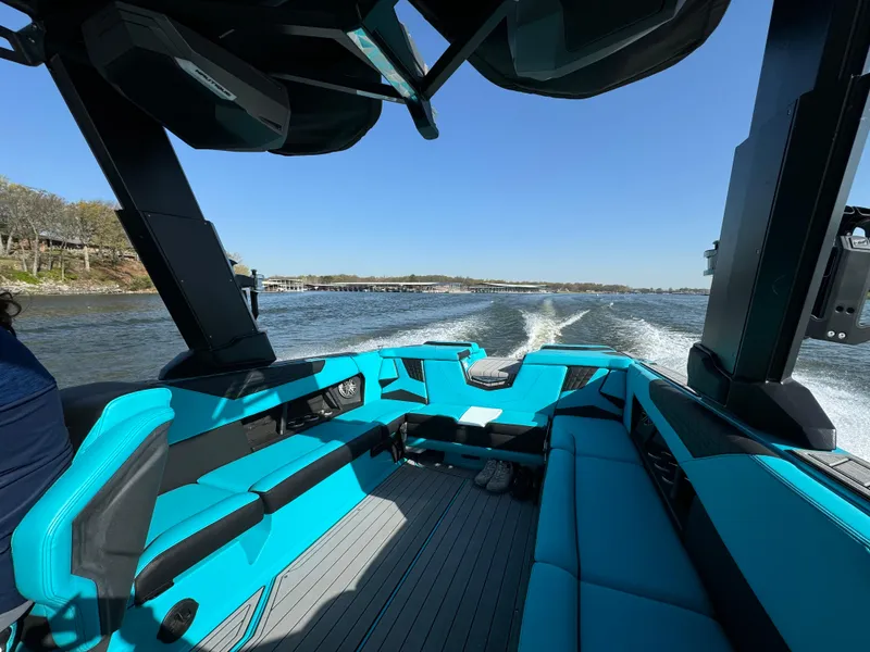 Slide: The Image of 2023 Nautique Super Air Nautique S25 boat interior with turquoise seating on a sunny day. - 21
