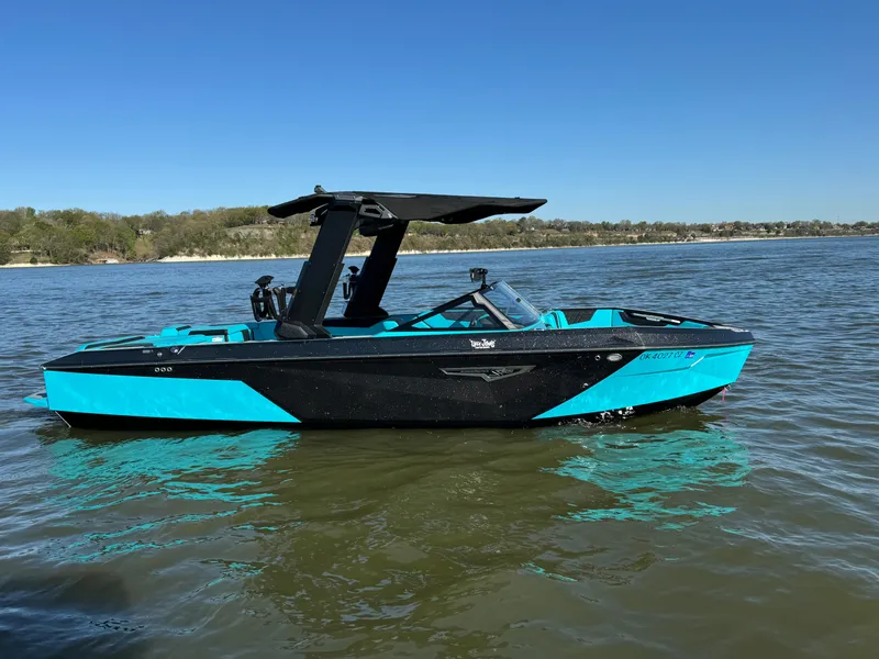 Slide: The Image of 2023 Nautique Super Air Nautique S25 boat on a lake under clear blue skies. - 3