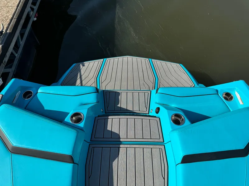 Slide: The Image of 2023 Nautique Super Air Nautique S25 boat deck with vibrant blue seating and cup holders. - 5