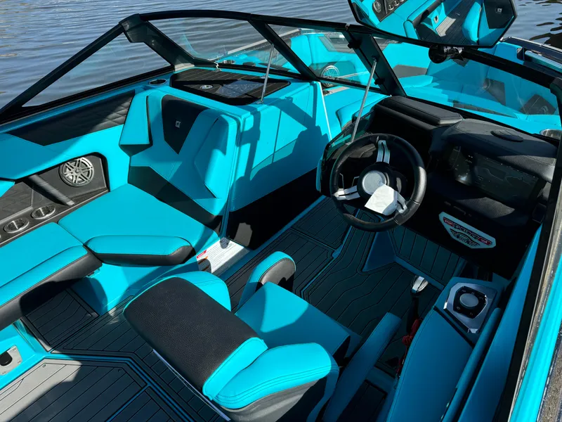 Slide: The Image of 2023 Nautique Super Air Nautique S25 interior with vibrant blue seating and modern dashboard. - 8
