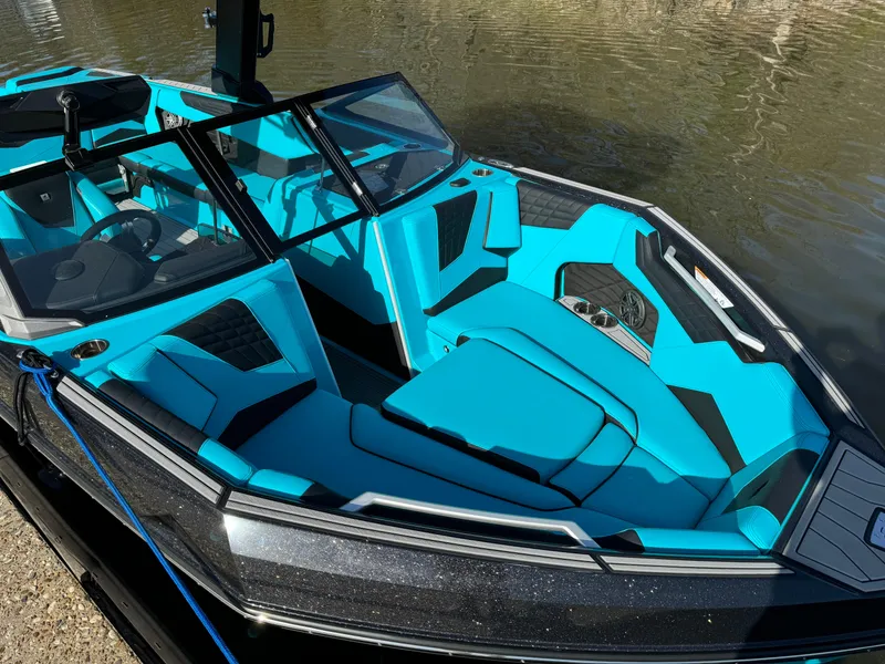 Slide: The Image of 2023 Nautique Super Air Nautique S25 boat with vibrant blue interior on calm water. - 9
