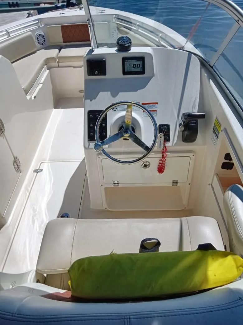 Slide: The Image of 2021 Cobia 220 Dual Console boat interior with steering wheel and seating. - 4