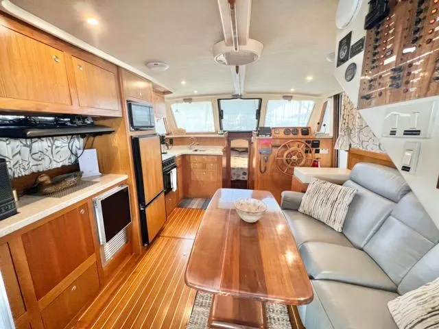 Slide: The Image of 2002 Mainship 390 Trawler interior with wood finishes, kitchen, and seating area. - 18