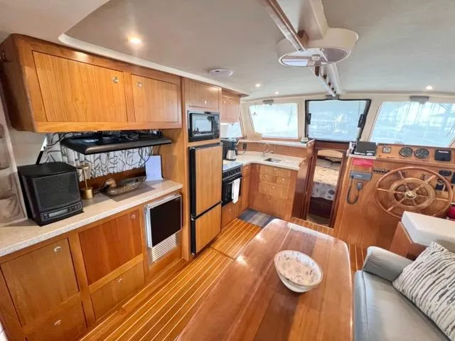 Slide: The Image of 2002 Mainship 390 Trawler interior with wooden cabinetry, dining area, and helm station. - 19