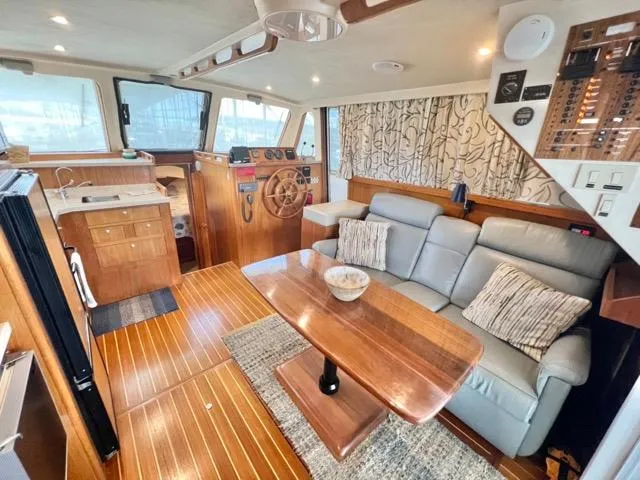 Slide: The Image of 2002 Mainship 390 Trawler interior with wood flooring, cozy seating, and nautical decor. - 20