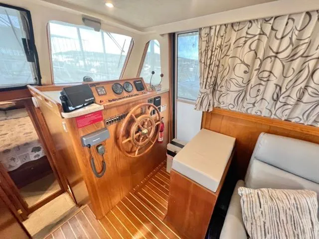 Slide: The Image of 2002 Mainship 390 Trawler helm with wooden steering wheel and nautical instruments. - 25