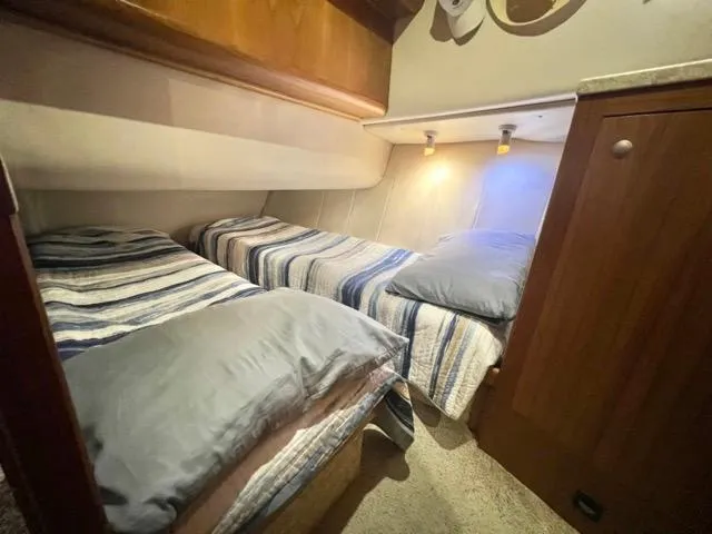 Slide: The Image of 2002 Mainship 390 Trawler cabin with twin beds and striped bedding. - 36