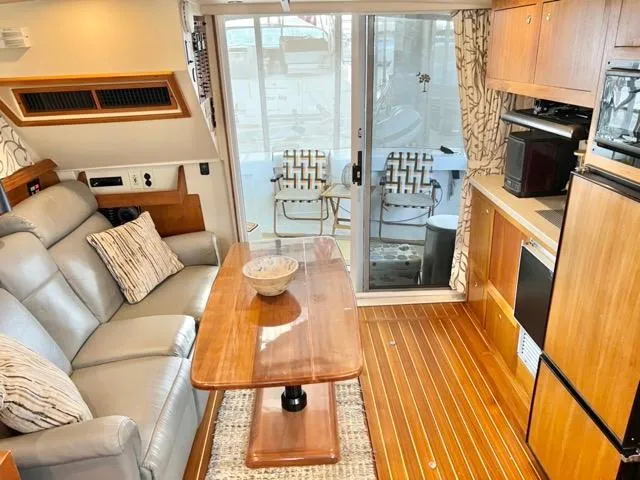 Slide: The Image of 2002 Mainship 390 Trawler interior with cozy seating, wooden table, and modern kitchen amenities. - 38