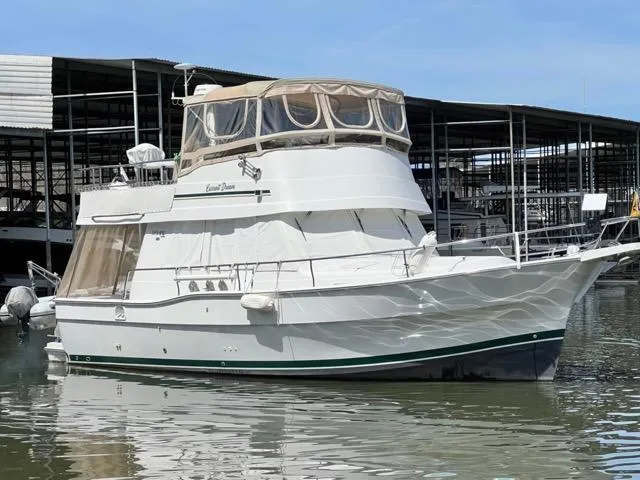 Slide: The Image of 2002 Mainship 390 Trawler docked at marina, featuring spacious upper deck and classic design. - 4