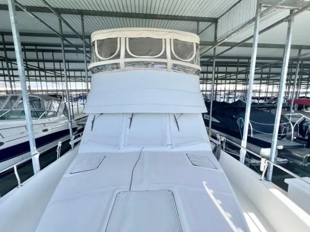 Slide: The Image of 2002 Mainship 390 Trawler in covered marina, showcasing spacious deck and flybridge. - 49
