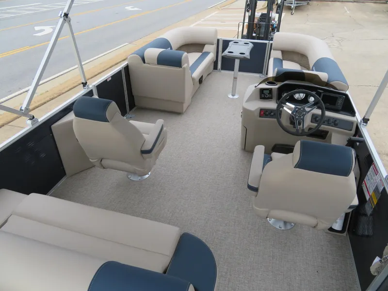 Slide: The Image of 2025 Bennington 22SSB pontoon boat interior with beige and navy seating, steering console, and table. - 17