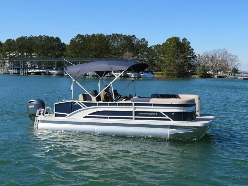 Slide: The Image of 2025 Bennington 22SSB pontoon boat on a serene lake with trees in the background. - 23