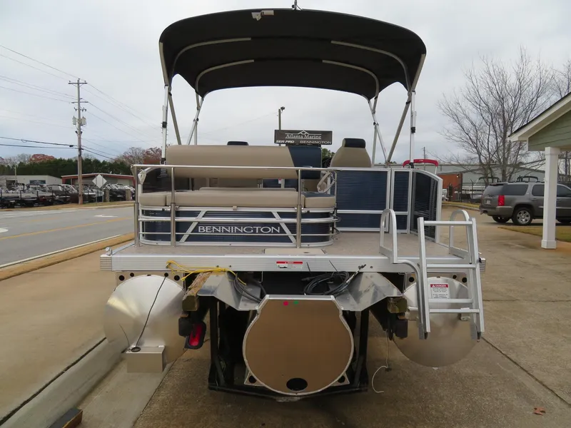 Slide: The Image of 2025 Bennington 22SSB pontoon boat with canopy, parked on a concrete driveway. - 6