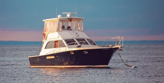 The Image of 1985 Egg Harbor 37 Convertible yacht anchored on calm water at sunset. - 0